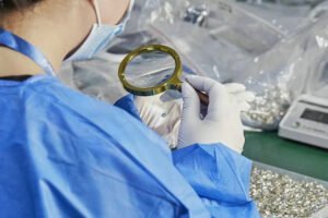 Quality control inspector using a magnifying glass to check gemstone details on premium press-on nails.